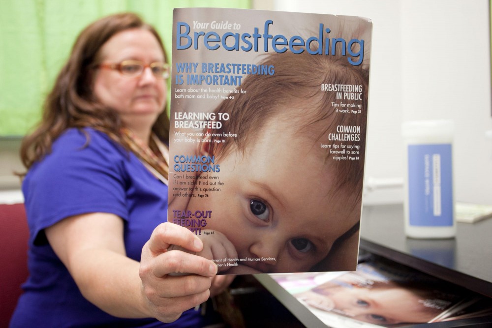 Susan Warfield holds up an informational magazine inside the lactation room in Appleby Hall Tuesday evening.  Since breast pumping can take around twenty minutes there is a desk filled with reading material to educate women who utilize the room.